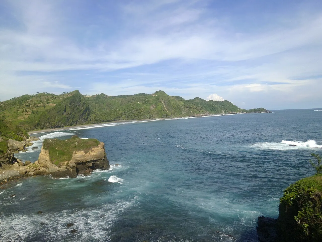 Pantai Menganti dengan tebing dan mercusuar di kejauhan